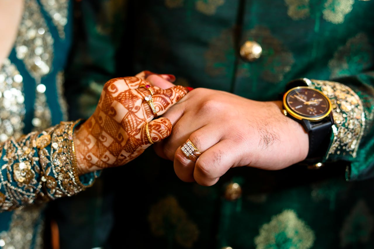 Close-up of a couple's hands adorned with henna and rings during an Indian wedding ceremony.